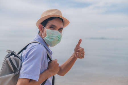 People wear medical mask thump up travel on beach safety covid19の写真素材