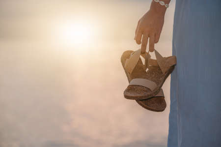 woman holding sandals walking on the beachの写真素材