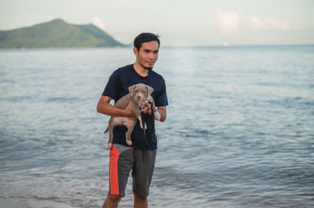 Man and dog travel on sea beachの写真素材