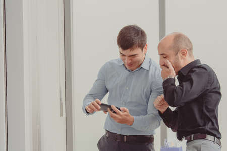 Two businesspeople looking phone trading onlineの写真素材