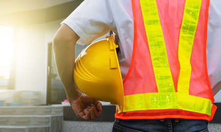 Closeup hand holding hard hat at home construction backgroundの写真素材