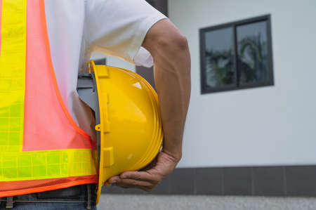 Closeup hand holding hard hat at home construction backgroundの写真素材
