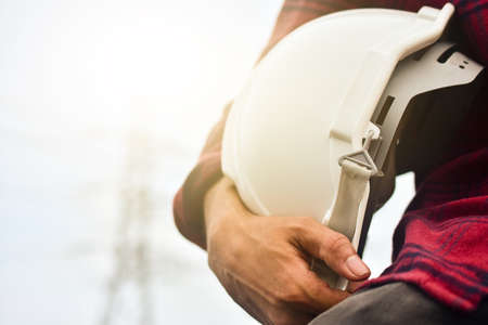 Technician holding white hat safety hard hat sunlight backgroundの写真素材
