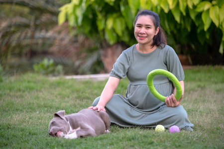 Pregnant woman sitting with dog at home, American bully dog puppy funny and cute, Dog mom happy familyの写真素材