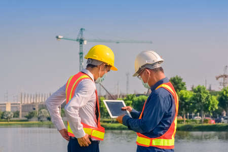 Asian team Construction engineers supervising progress of construction project stand on new factory, Engineering Consulting People on construction site Building inspector.の写真素材