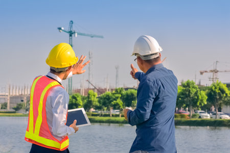 Asian team Construction engineers supervising progress of construction project stand on new factory, Engineering Consulting People on construction site Building inspector.の写真素材