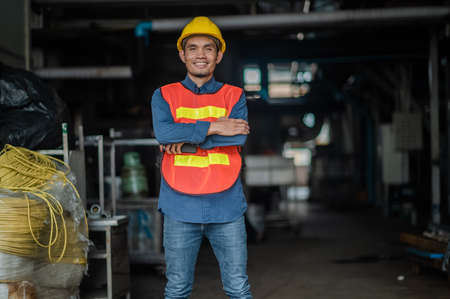 Confident Asian engineer standing in  factory , Asia worker employee in hard hat safety work in factoryの写真素材