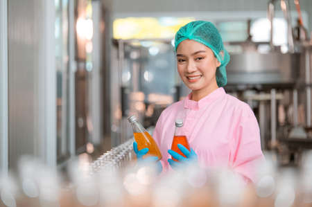 Asian woman employee working Food quality control in Factory and worker inspecting production line beverage tanker in of dairy factory Concept food industryの写真素材