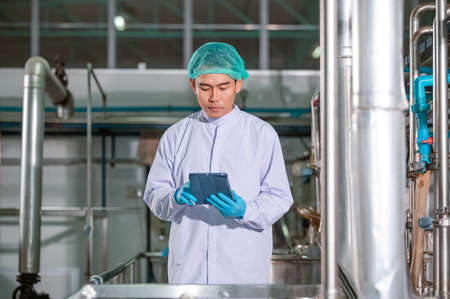 Asian man engineer factory Professional technologist using tablet in production plant checking productivity and quality.の写真素材