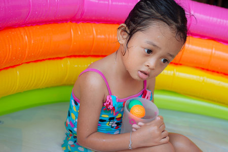 Kids playing in colorful paddling pool in backyardの写真素材