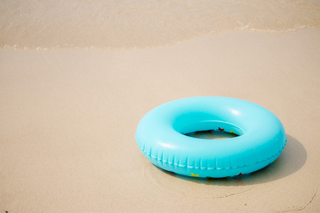 Blue inflatable swim ring on sand beachの写真素材