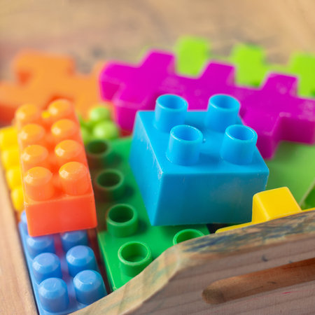 Toy colorful plastic blocks on wooden floor background