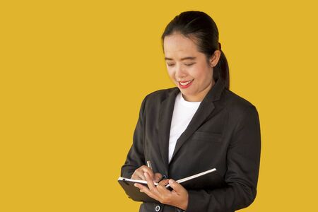 Business woman holding notebook isolated on yellow background.の写真素材