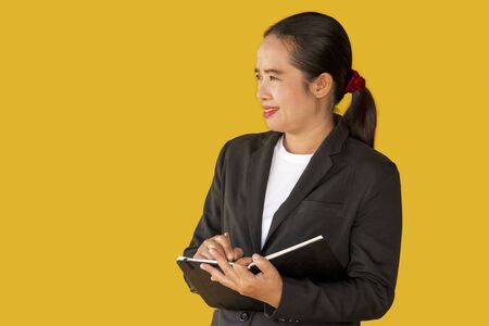 Business woman holding notebook isolated on yellow background.の写真素材