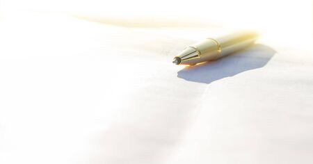 Low angle view of golden pen lying on white sheet of paper in a folder with another set of paperworkの写真素材