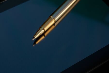 Low angle view of golden pen lying on tabletの写真素材