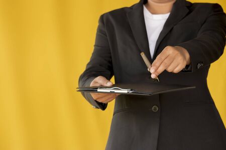Business woman handed the pen to customer isolated on yellow background.の写真素材