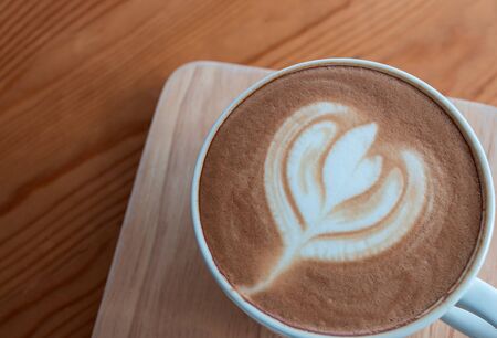 Latte coffee cup with latte art on wooden table in coffee shop.の写真素材
