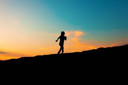 The silhouette of a girl running on a hill In the sunset skyの写真素材