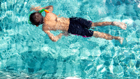 The boy is very happy to swim in the pool. Family vacation concept
