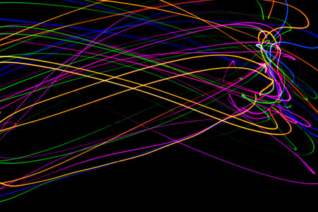 Multi color light painting photography, swirl and curve of blue, green and red light against a black...