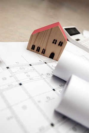 real estate and property, architecture, building, construction concept - Tiny house model on an architect's deskの写真素材