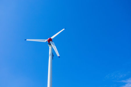 The wind turbine generates an environmentally friendly electricity in the bright blue sky.