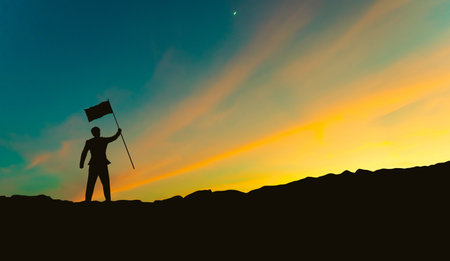 silhouette of businessman with flag on mountain top over sunset sky background, business, success, leadership and achievement conceptの写真素材