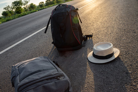 Backpacks, hats, sneakers on the highway with golden light of the sun, Travel conceptの写真素材