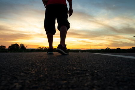 Silhouette of a man walking on the highway At the time of the sun set, Concept of vacation and travelの写真素材