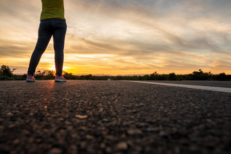Women wearing t-shirts, jeans, sneakers and hats at sunset, standing along the highway to travel, Happy mood, Vacation conceptの写真素材