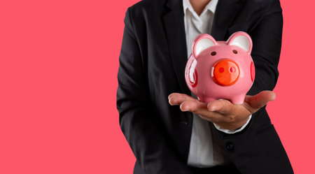 Financial planning concept, Business person holding piggy bank in hand isolated on magenta pink.の写真素材