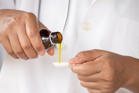Hands of Medical person pouring syrup medicine into clear spoonの写真素材