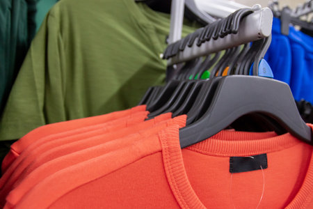 Fashion clothes on clothing rack - bright colorful closet. Close-up of colorful choice of trendy male wear on hangers in store closet or shopping mall.の写真素材