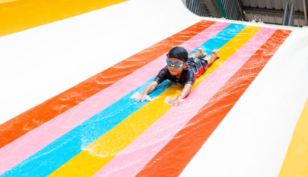 Happy cheerful kids splashing water on water slide at aqua parkの写真素材