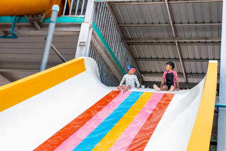 Happy cheerful kids splashing water on water slide at aqua park