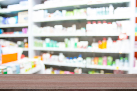 Wooden table top on blur images of medicines in pharmacies background - can be used for display or montague your products.Mock up for display of product.の写真素材