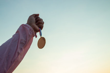 Concepts of victory, success, Woman wear pink long-sleeved shirts. Holds gold medal on beautiful sunset sky background.の写真素材