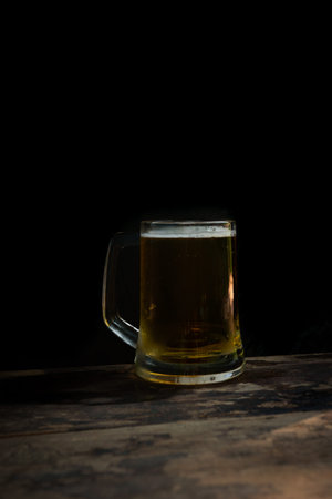 mug of beer with foam on dark backgroundの写真素材