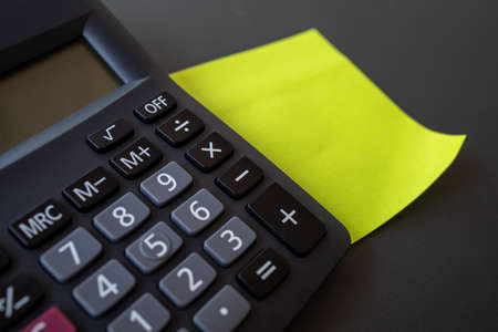 Finance concept, reminder paper and calculator on black backgroundの写真素材