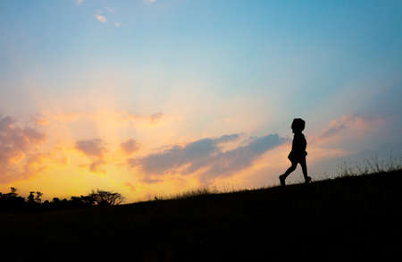 The silhouette of a girl running on the hill at sunsetの写真素材