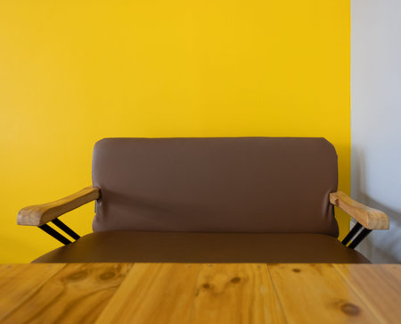 An empty brown sofa in a room with yellow walls