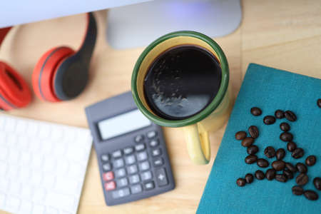 The work desk has a coffee cup and red headphones and office supplies.の写真素材
