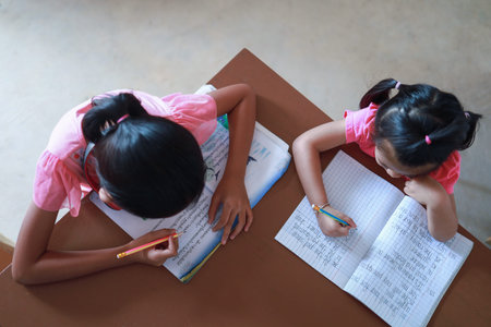 A cute Asian girl doing homework in her home during the day.