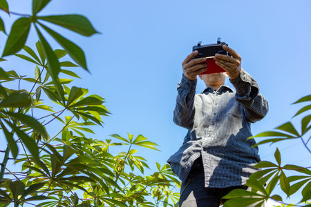 An Asian farmer uses agricultural drones to detect damage and growth of the crops he grows on his...