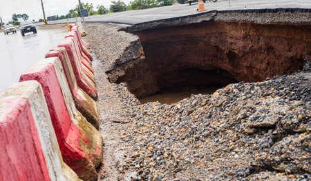 The road was destroyed by water erosion caused by heavy rain and flooding the road.の写真素材
