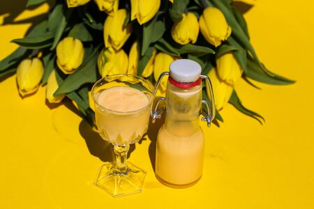 Eggnog with yellow tulips on a yellow backgroundの写真素材