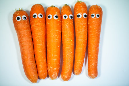 Carrots in a row with eyes, funny carrots, white backgroundの写真素材