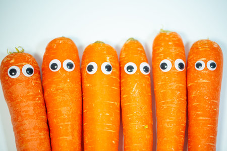 Carrots in a row with eyes, funny carrots, white background