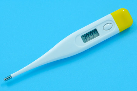 The electronic body thermometer displays a very high temperature of 39.9 Â° C (Celsius) on a blue backgroundの写真素材